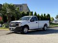 A white 2018 Ford F-150 pickup truck is parked with a single cab and bed showcasing chrome wheels and a sleek design