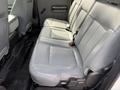 The interior of a 2011 Ford F-350 SD featuring a light gray leather bench seat with seat belts and a clean, spacious layout in the back row