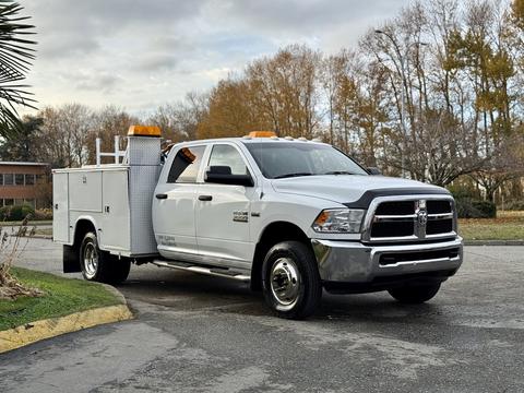 A white 2013 RAM 3500 truck with a utility bed and orange safety lights on top parked on a paved surface