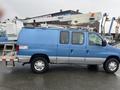 A blue 2006 Ford Econoline van with a utility lift mounted on its roof and equipment on the rear panel
