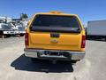 A yellow 2013 Chevrolet Silverado 1500 parked with a clear view of its rear end and taillights