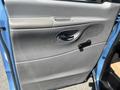 A close-up of the blue interior door panel of a 2005 Ford Econoline featuring a handle and a speaker grille