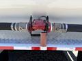 A red and silver valve assembly is mounted on a metallic surface with two large black hoses connected to it