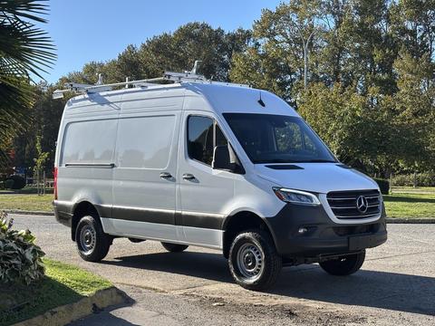 A 2024 Mercedes-Benz Sprinter 2500 van with a sleek design features a white body, black accents, and a roof rack for additional cargo space