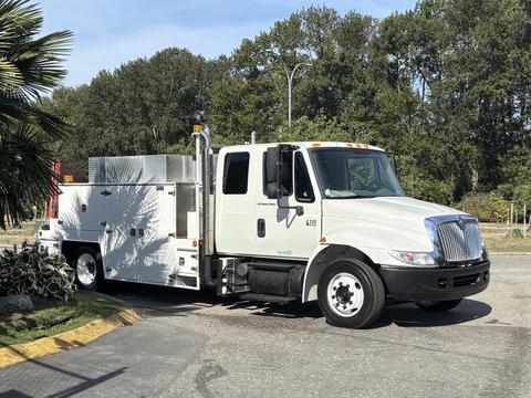 A white 2006 International 4300 utility truck with a service body and tool compartment visible on the side