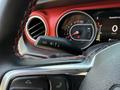 A close-up view of the steering wheel and dashboard of a 2021 Jeep Wrangler featuring the speedometer and controls for various functions