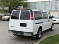 A 2004 Chevrolet Express van in white parked with a rear view displaying its large windows and no visible license plate