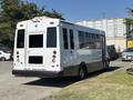 A white 2020 Chevrolet Express shuttle bus with rear tinted windows and a sign stating "PLEASE YIELD THANKS FOR THE BRAKE" on the back