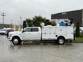 A 2024 RAM 5500 utility truck with an extended cab and a service body equipped with a hydraulic lift on the bed