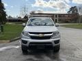 Front view of a 2018 Chevrolet Colorado with a white exterior and a prominent Chevrolet logo on the grill
