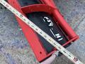 A red and black snowplow blade with measurement markings along its edge, showcasing its width and features of the plow system