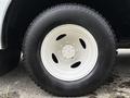 A close-up of a white rim with a large black tire mounted on a 2018 Ford Econoline showing a tread pattern and bolt holes on the rim