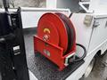 A red hose reel mounted on a vehicle platform with a black textured surface connected to a water hose