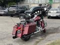 A red 2009 Harley-Davidson Road King motorcycle with a black seat and a large windshield parked on a pavement with visible chrome accents and saddlebags