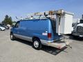 A blue 2005 Ford Econoline van with a service ladder attached to the roof and a utility bucket mounted on the back