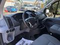 Interior view of a 2016 Ford Transit 150 showing the steering wheel dashboard and front seats in gray upholstery