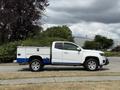 A white 2017 Chevrolet Colorado truck with a blue and silver utility bed and alloy wheels parked on a paved surface