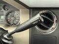 A black gear shift lever labeled Tow Haul in a vehicle's interior with gauges and air vent visible in the background