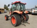 A red and orange 2010 Kubota M6040 tractor with large rear tires and a cab, showcasing its rear view and attachment points for implements