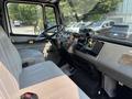 Interior of a 1999 Freightliner FL80 featuring two gray seats a steering wheel and various dashboard controls