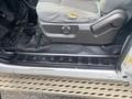 A close-up of the driver's side interior of a 2014 Ford F-350 SD featuring the seat the floor mat and the door sill with the words Super Duty visible