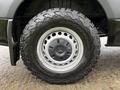 A close-up of a black wheel and tire from a 2022 Mercedes-Benz Sprinter featuring a rugged tread pattern and the Mercedes-Benz logo on the hubcap