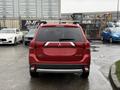 A red 2016 Mitsubishi Outlander viewed from the rear with a simple design and distinctive taillights