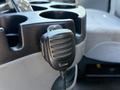 Close-up of a black Icom microphone attached to a console with multiple cup holders inside a 2006 Ford Econoline