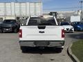 A white 2018 Ford F-150 pickup truck viewed from the rear with the tailgate down and rear lights visible