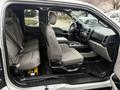 The interior of a 2015 Ford F-150 showing front and rear seats in gray fabric with a center console and dashboard features