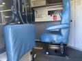 A blue driver's seat in a 2011 Chevrolet Express with controls and a safety equipment panel visible on the wall behind it