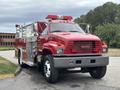 A red 2002 GMC C7500 fire truck featuring a prominent grille a large cab and emergency lights on the roof