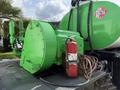 A bright green pump attached to a truck with a red fire extinguisher and several hoses leading from it