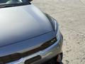 A silver 2024 Kia Forte5 featuring a sleek hood design and a distinctive front grille with a GT emblem