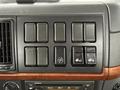 Interior dashboard of a 2012 Volvo VNL featuring various buttons and switches arranged in a panel with a wooden trim and a car stereo below