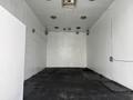 A 2012 Ford F-550 truck parked inside an empty white room with a black floor and minimal lighting