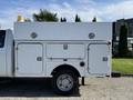 A 2012 Ford F-350 SD utility truck with a white service body featuring storage compartments and a rooftop light installed
