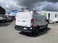 A white 2019 Ford Transit van with a roof rack and a sliding door visible from the rear