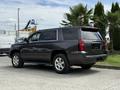 A gray 2017 Chevrolet Tahoe parked from the side showcasing its SUV design and chrome wheels