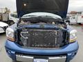 A blue 2006 Dodge Ram 2500 with its hood raised revealing the engine compartment and exposed parts such as the radiator and various mechanical components