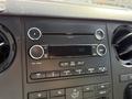 The interior dashboard of a 2015 Ford F-550 featuring a stereo system with knobs buttons and an auxiliary input
