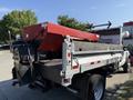 A 2008 Ford F-450 SD with a flatbed and a red salt spreader attached to the rear