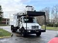 A 2015 Freightliner M2 bucket truck with a white body and a black chassis featuring an extended platform for accessing high areas