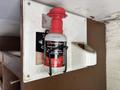 A red and black spray canister labeled DYNAMIC secured in a white wall-mounted holder