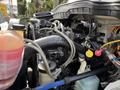 Engine compartment of a 2011 International 4300 with various pipes hoses and components visible including a coolant reservoir and electrical connections