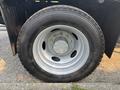 A close-up of a silver wheel and tire from a 2009 Ford F-550 with visible lug nuts and a textured tread pattern
