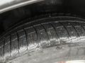 A close-up view of a black tire showing detailed tread patterns and water droplets on the surface