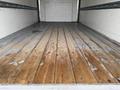 A wooden floor inside a 2022 Ford Econoline van with visible wear and tear showing scratches and stains on the surface