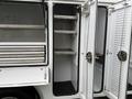 A white 2024 RAM 5500 with an open cargo area featuring gray shelves and doors designed for easy access and storage