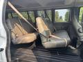 The interior of a 2021 Chevrolet Express showing two rows of grey vinyl seats equipped with seatbelts in a spacious cabin setting